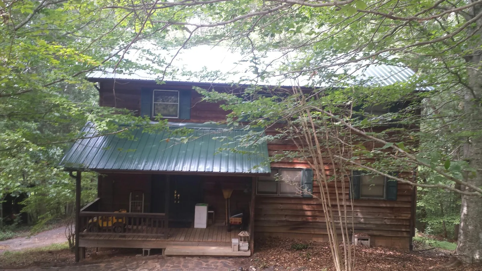 Green metal roof and covered porch on a log cabin in Tucker