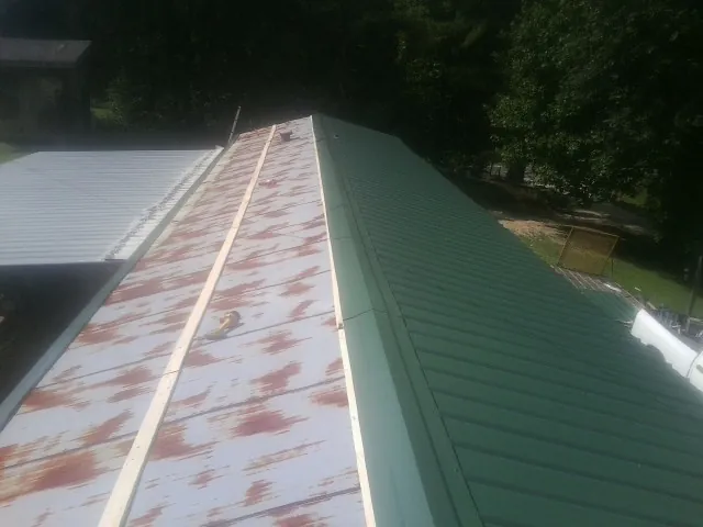 Old rusted panels beside newly installed green metal roofing — Wind Damage Roof Repair by Roofing Brothers in Tucker