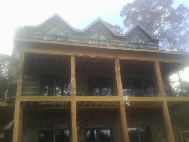 Dormers and porch framing on a large log home under construction — Roof Coating work by our crew in Tucker