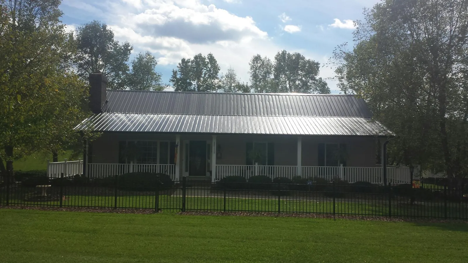 Gray metal roof on a brick ranch with a full width front porch — Gutter Guard Installation work by our crew in Tucker