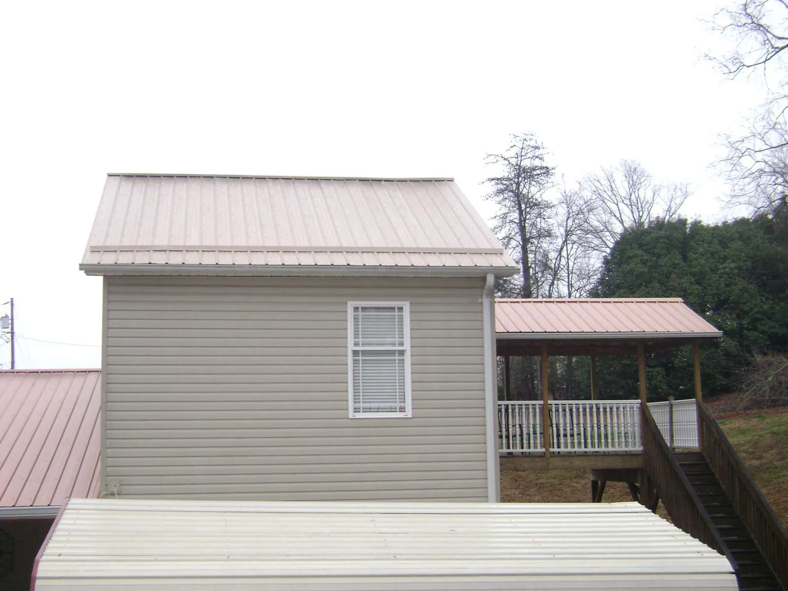 Tan metal roofs on a two story addition and attached porch, from a Roof Replacement job in Tucker
