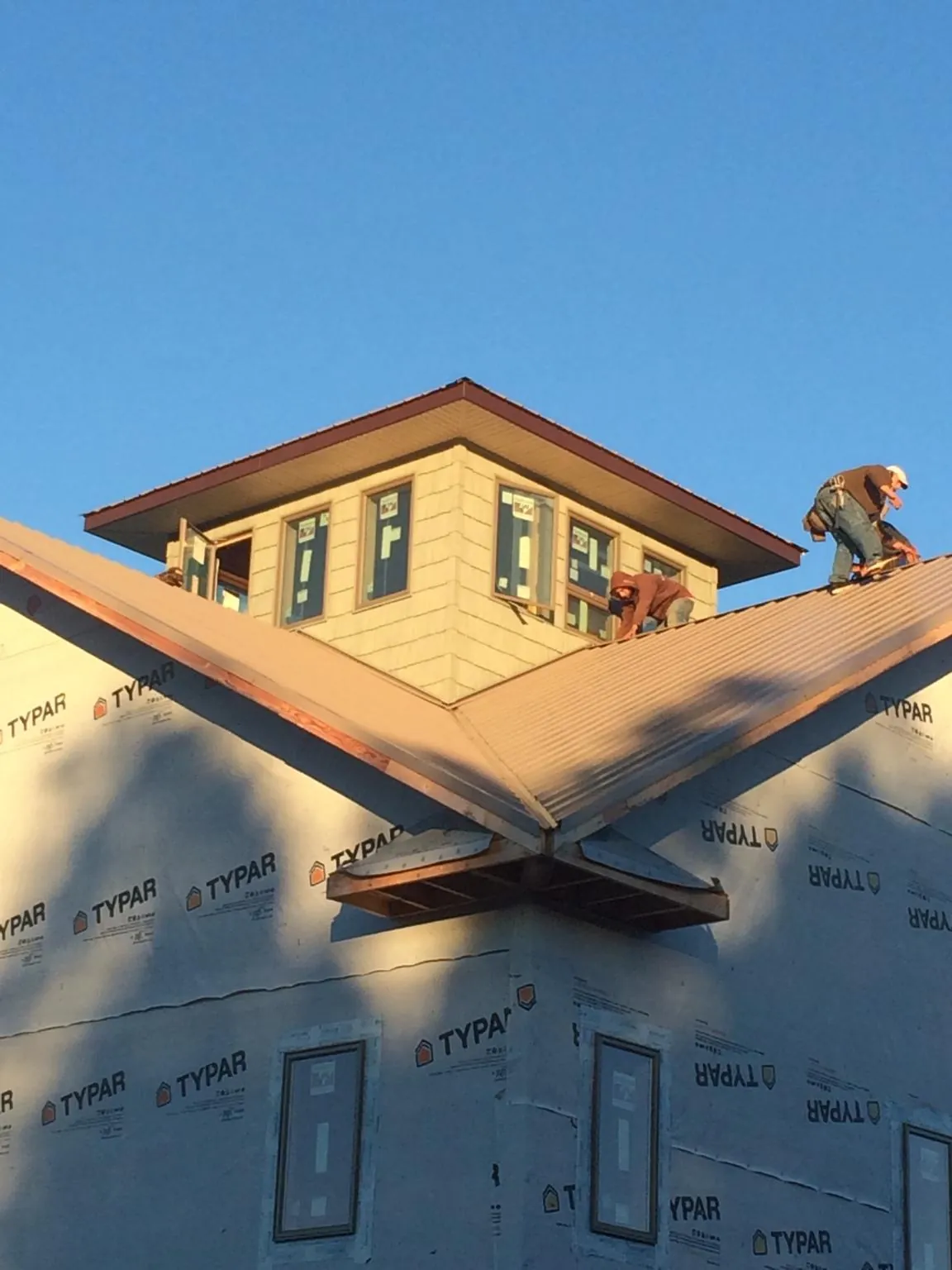 Roofers working around a rooftop cupola on a new metal roof at sunset — Roof Waterproofing in Tucker by Roofing Brothers